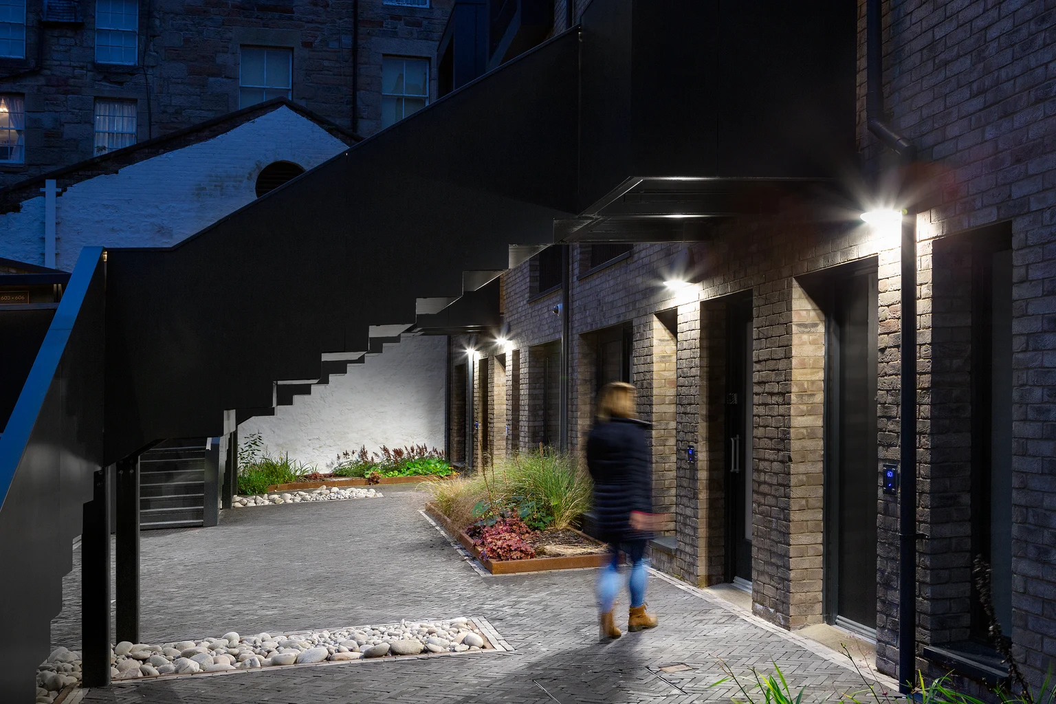 Les luminaires muraux aux entrées des bâtiments offrent une orientation claire et renforcent le sentiment de sécurité des résidents et des visiteurs la nuit.