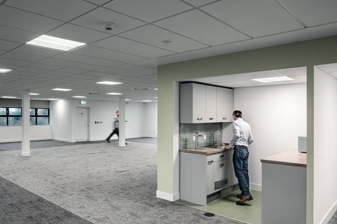 Mehrere Deckenleuchten sorgen für eine gleichmäßige künstliche Beleuchtung im Raum. Zusätzlich fällt Tageslicht durch die Fenster auf der linken Seite ein.