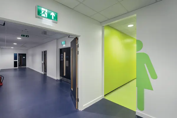 Een gang van een onderwijsacademie met de noodverlichting boven de opening van de gang