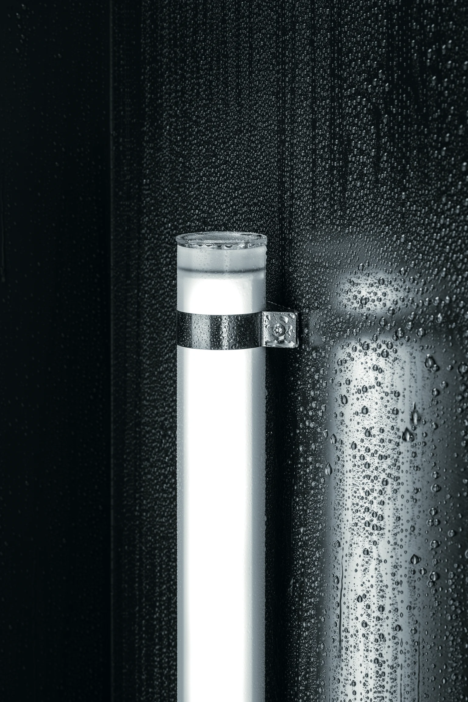 L'apparecchio illuminotecnico TUBILUX su una parete bagnata e scura genera una luce fredda e uniforme, mettendo in evidenza le gocce d'acqua nei dettagli.