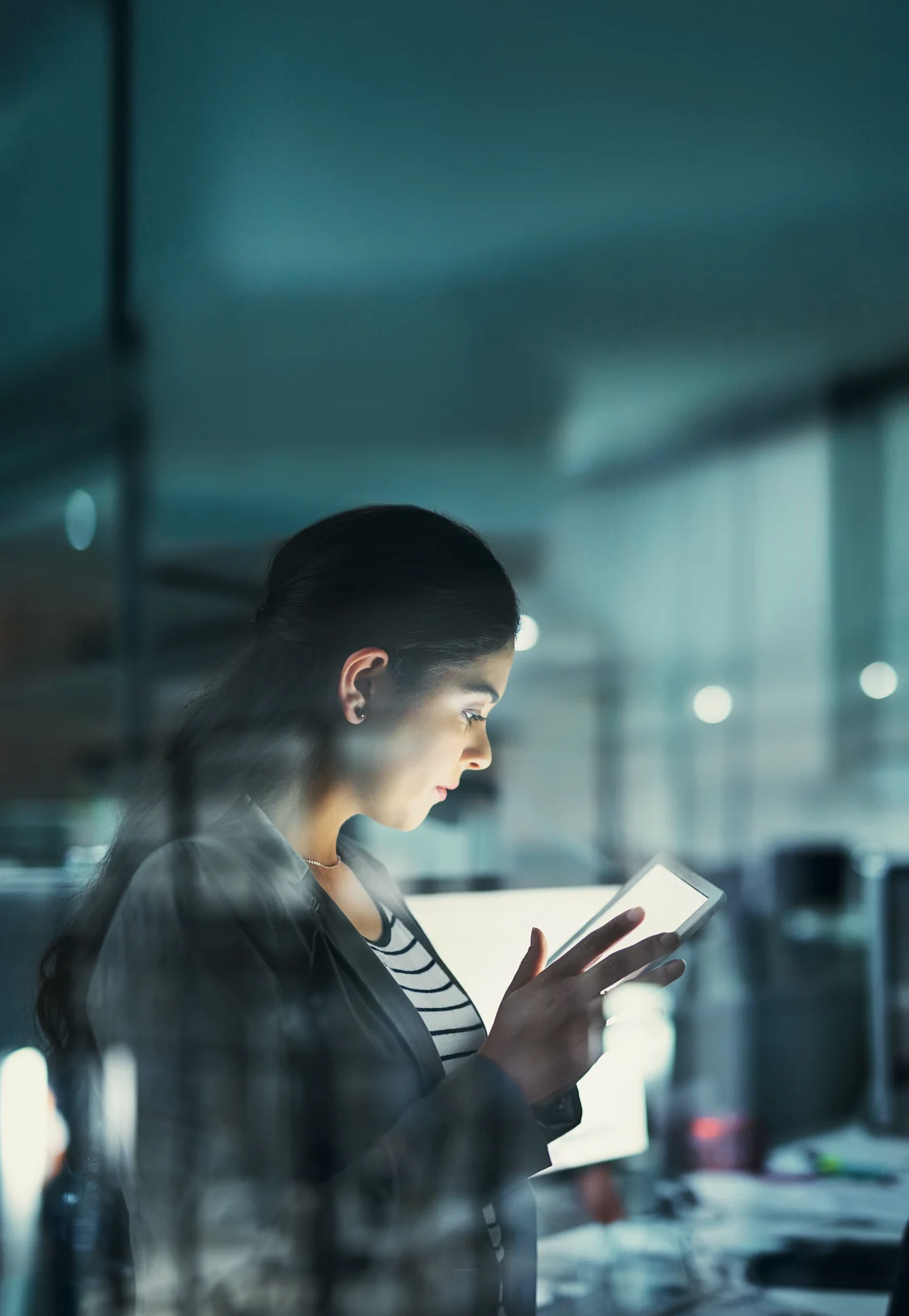 Eine Frau liest in einer Büroumgebung auf einem Smartphone.
