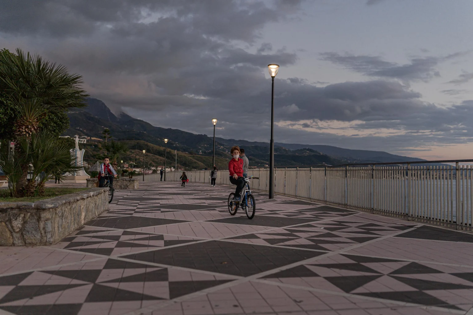 Una passeggiata con un ciclista nelle prime ore del buio, illuminata dolcemente da un apparecchio illuminotecnico testapalo di Thorn