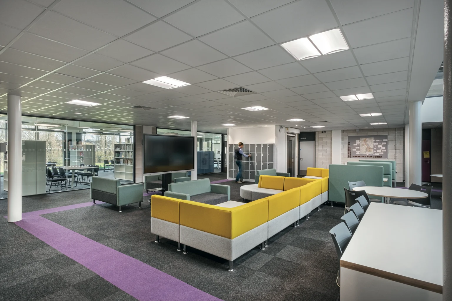 Spazio educativo moderno con sedute vivaci, pareti divisorie in vetro e apparecchi illuminotecnici a soffitto incassati per un’illuminazione brillante e uniforme. Progettato per favorire la collaborazione e un ambiente di apprendimento confortevole.