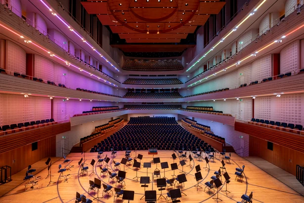 The concert hall in Lucerne illuminated with colourful Zumtobel lights. In the foreground are the chairs for the orchestra.