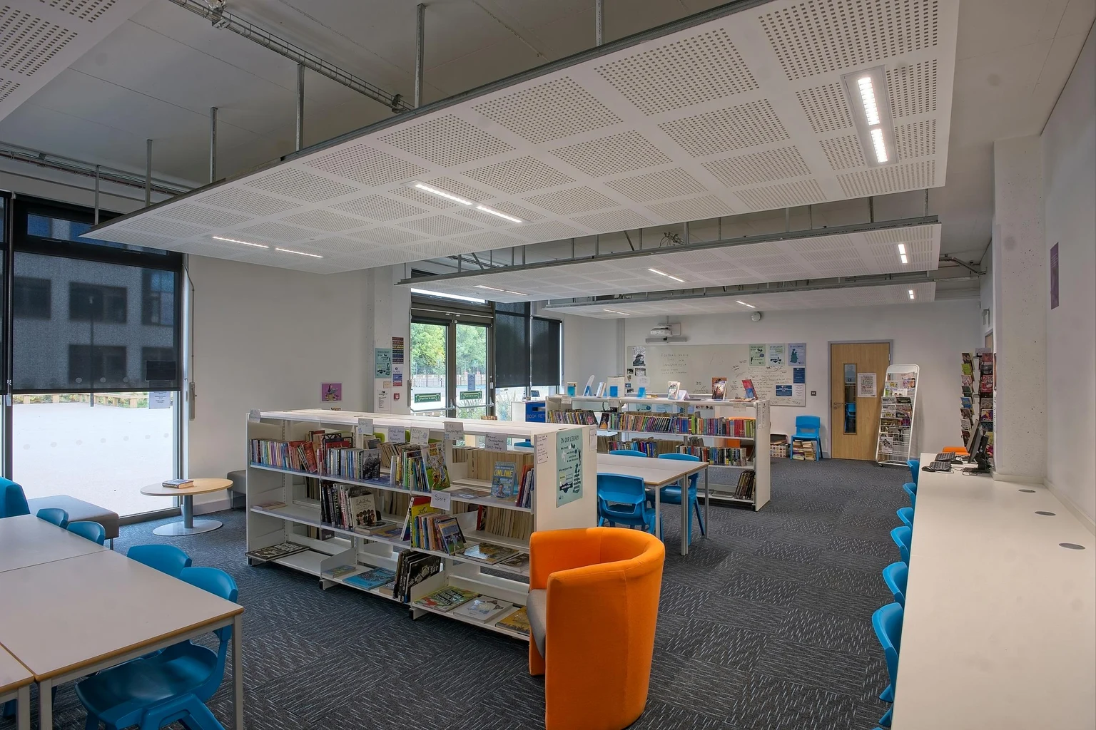 Una biblioteca moderna con illuminazione brillante, sedute colorate e scaffali ben organizzati, che crea uno spazio di apprendimento accogliente e funzionale. Il design enfatizza comfort, accessibilità e produttività.