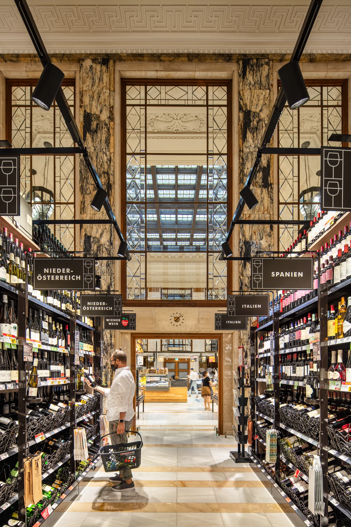 TRACKS Beleuchtungssystem sorgt für gleichmäßiges Licht in einem eleganten Weingeschäft mit hölzernen Regalen und Marmorsäulen.