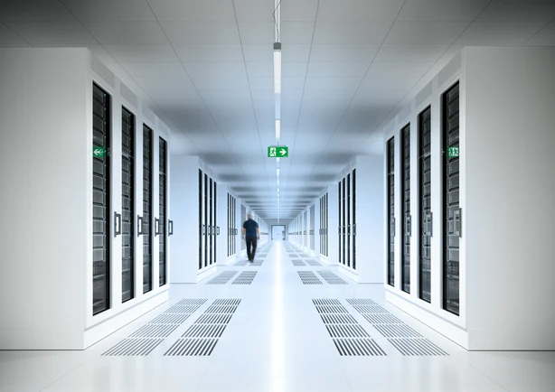 Zu sehen ist ein Data Center mit moderner Beleuchtung in einem langen Gang. 