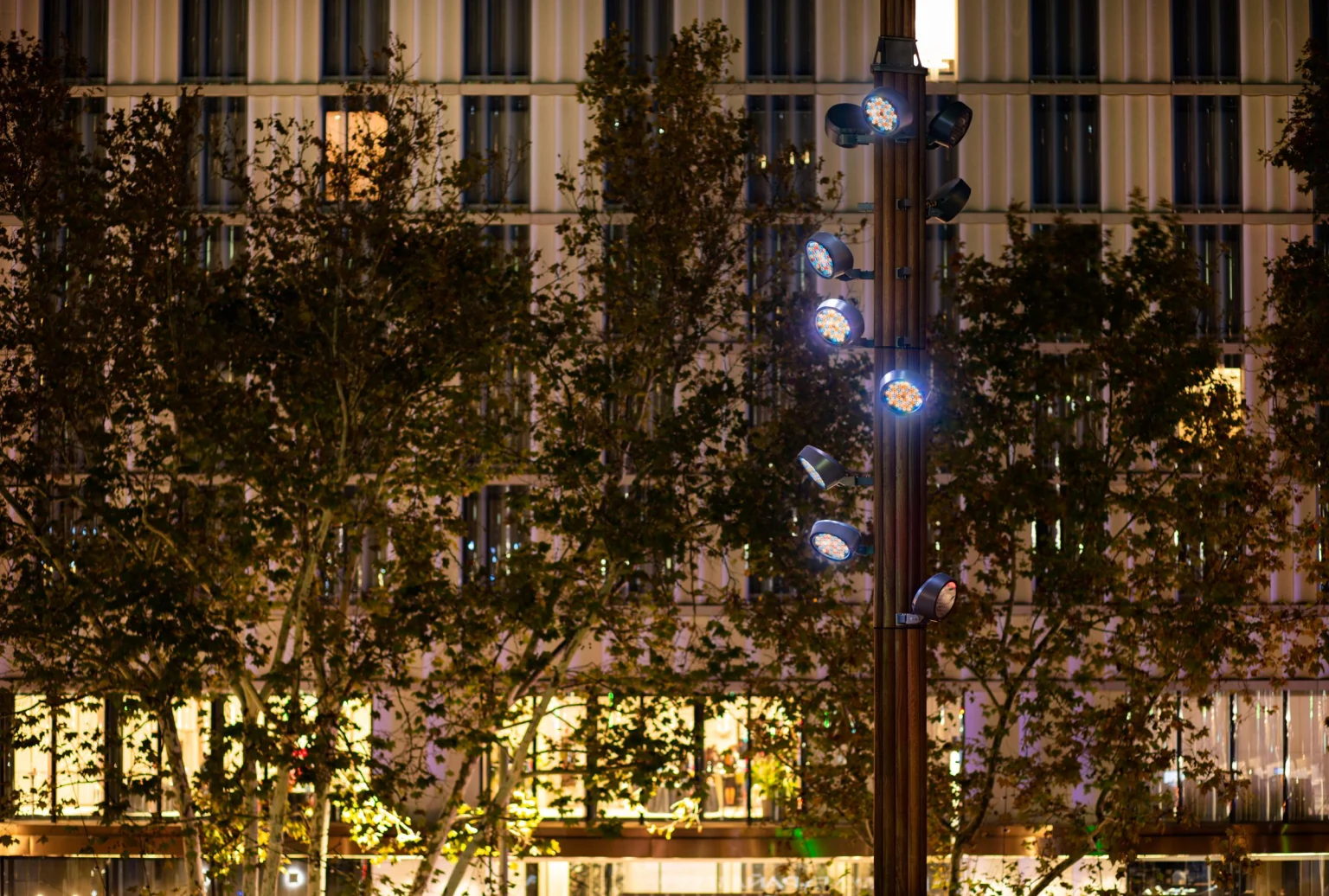 Witte ledspots op de mast zorgen voor een heldere en efficiënte verlichting van de omgeving, waardoor de zichtbaarheid en het comfort van de mensen op het plein worden verbeterd.