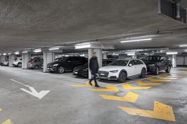 Grundeli-Parkplatz mit geparkten Autos und einer Person, die davor steht