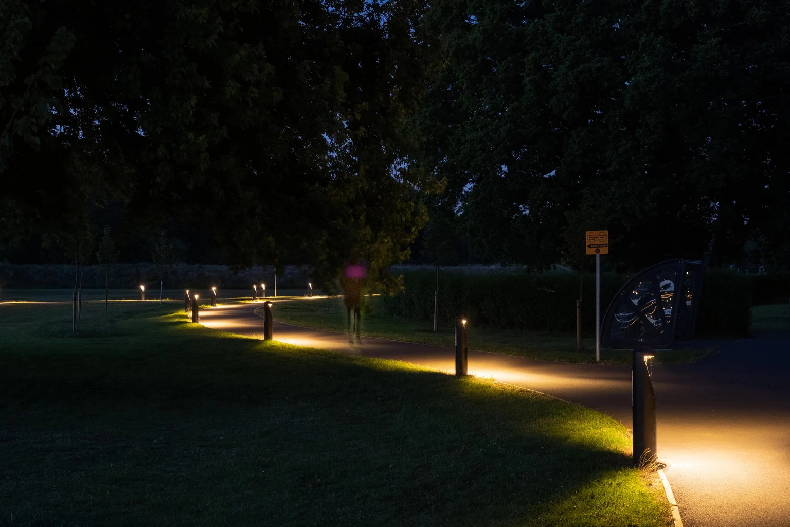 Een pad in een park dat 's nachts wordt verlicht door bolderverlichting met zacht licht voor bewegwijzering en veiligheid