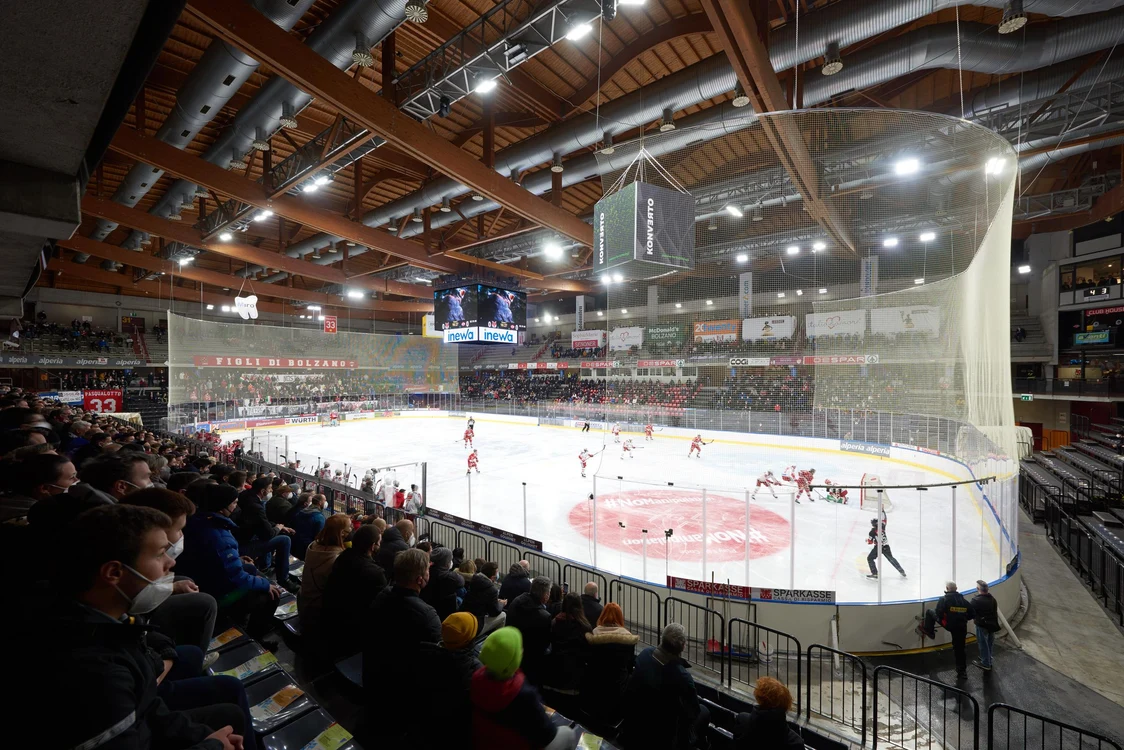 Partita di hockey su ghiaccio indoor con giocatori sul campo e tifosi sugli spalti