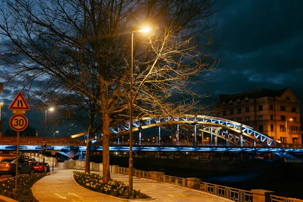 A bridge within a city at night highlighted with RGBW lighting