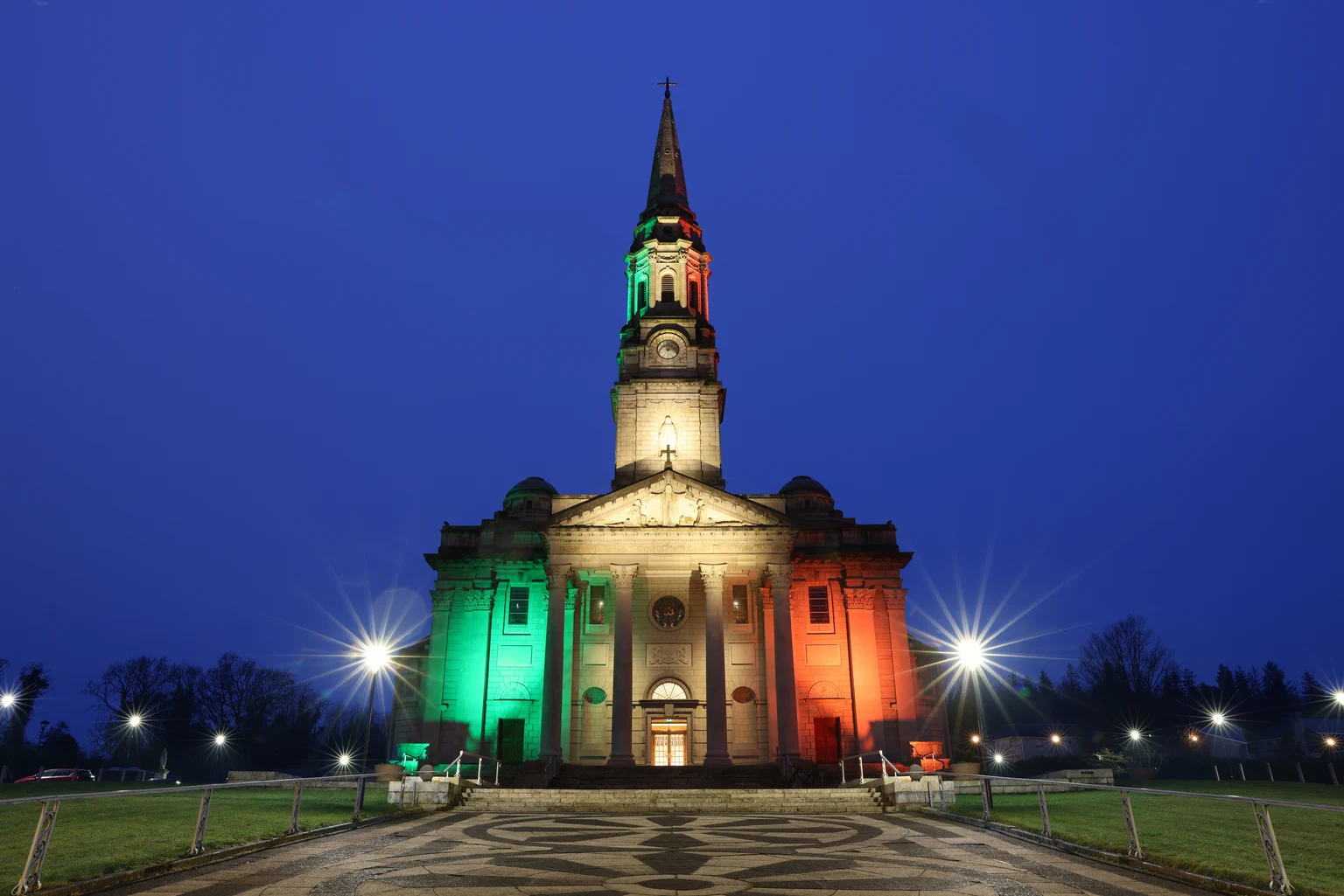 Dynamische buitenverlichting baadt de kerkgevel in levendige kleuren, waardoor het gebouw 's nachts een opvallend herkenningspunt wordt en verschillende lichtsferen mogelijk zijn, afhankelijk van de gelegenheid.