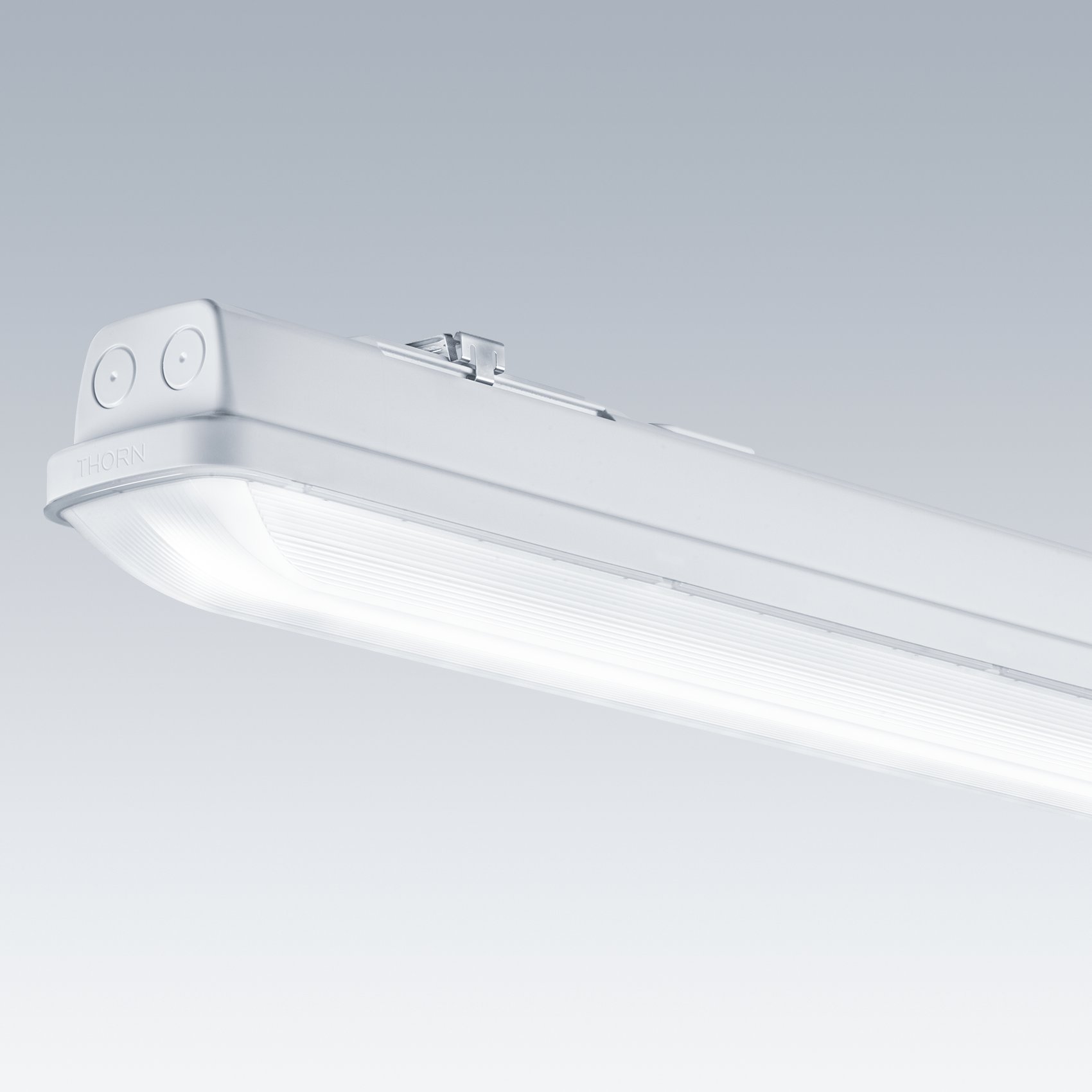 Een strakke witte led-plafondlamp met een rechthoekig design en afgeronde hoeken. De armatuur is te zien tegen een grijs verlopende achtergrond, waardoor het minimalistische en duurzame ontwerp voor industrieel of commercieel gebruik goed tot zijn recht komt.