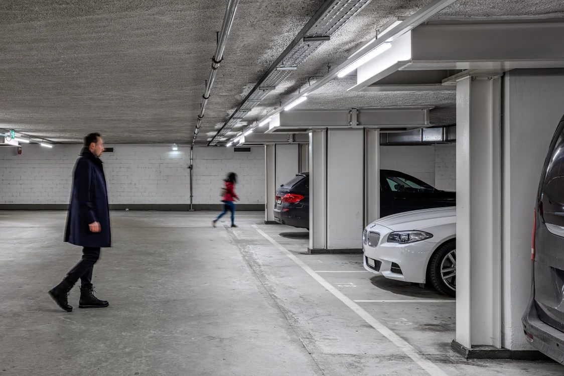 Parcheggio coperto illuminato con auto parcheggiate e persone