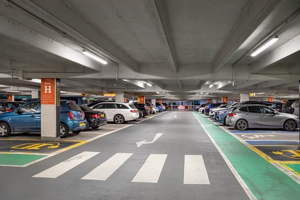 Overdekte parkeerplaats bij Gatwick Airport met geparkeerde auto's en een zebrapad