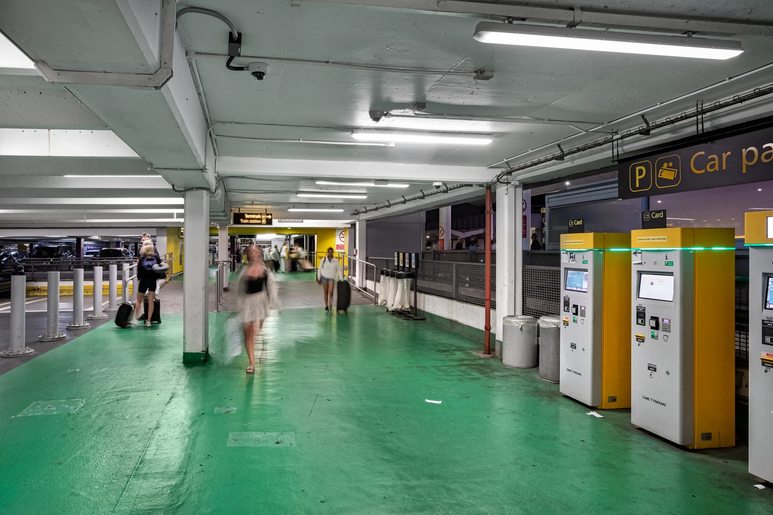 Betaalautomaten op de parkeerplaats van Gatwick Airport met bezoekers in beeld die terugkeren naar of hun voertuigen verlaten