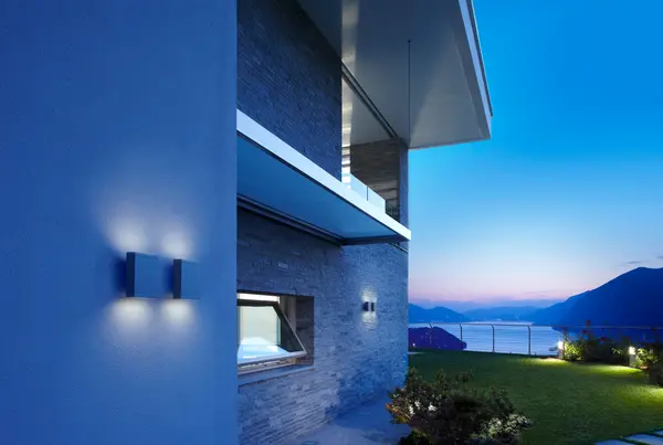 A residential building with outdoor wall lighting for wayfinding in the hours of darkness