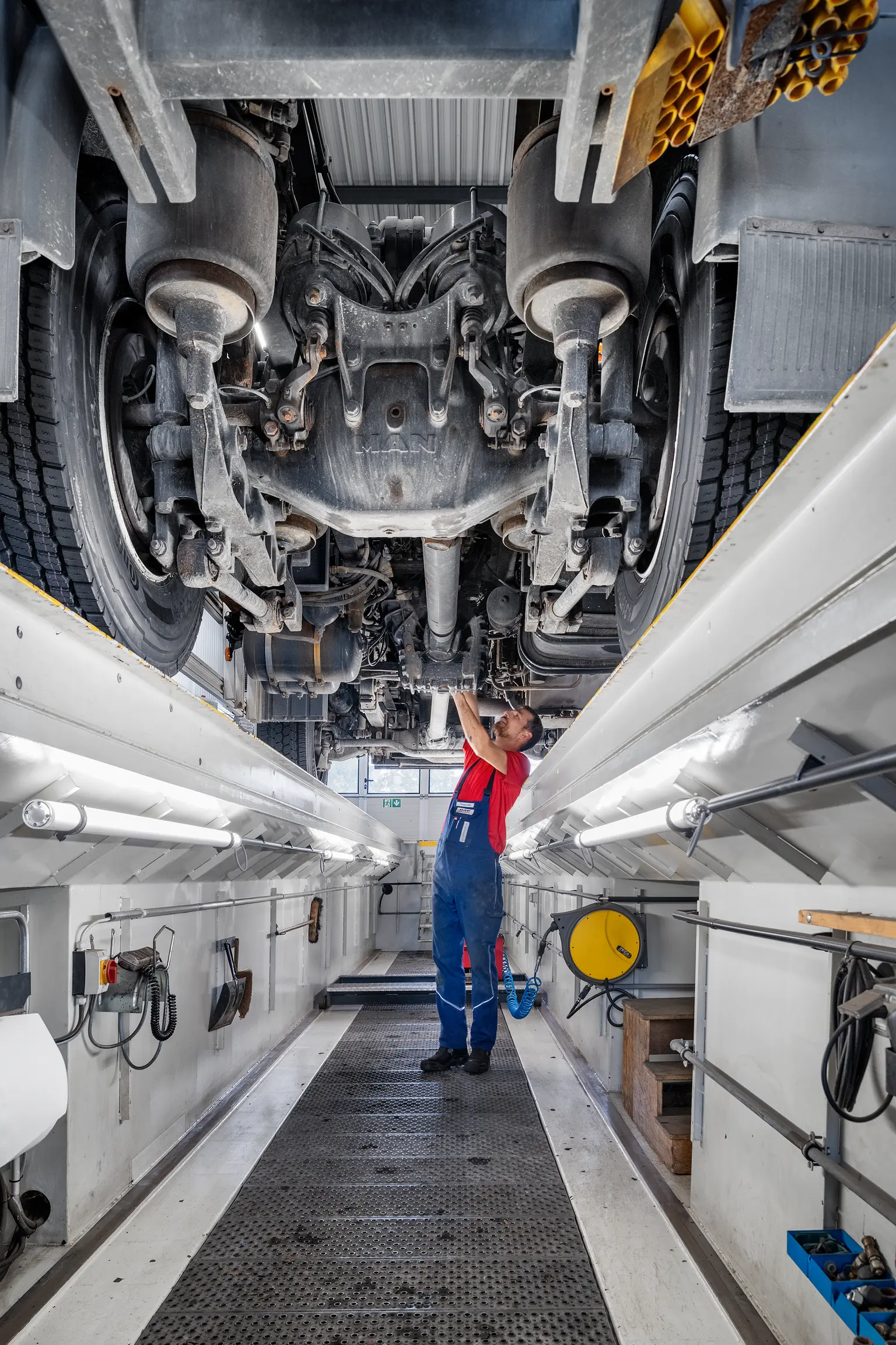 Mechaniker arbeitet unter der Hebebühne an einem Auto mit der neuen Beleuchtung nach der Sanierung