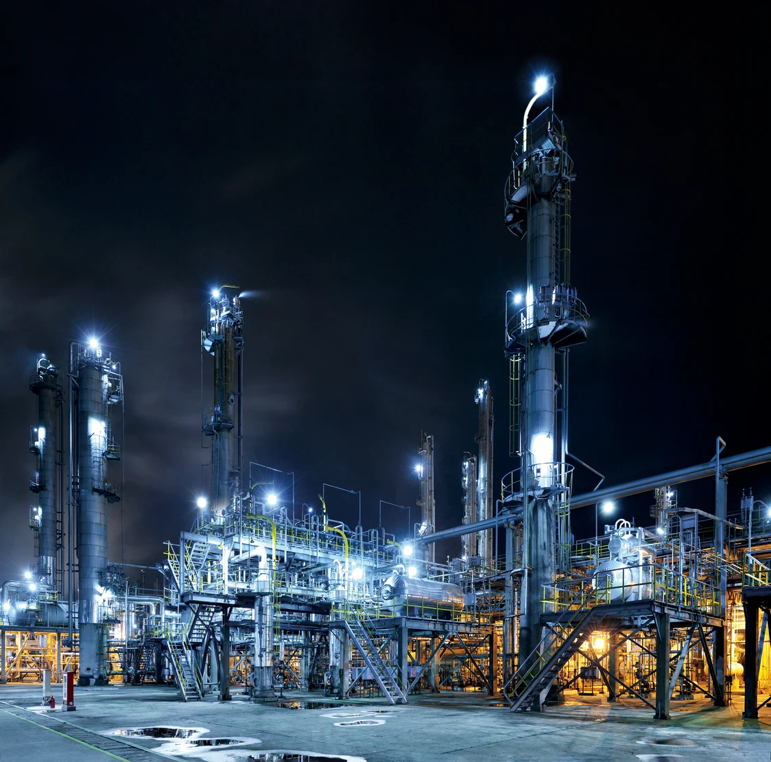 Ein gut beleuchtetes Industriegelände mit Stahlkonstruktionen bei Nacht.