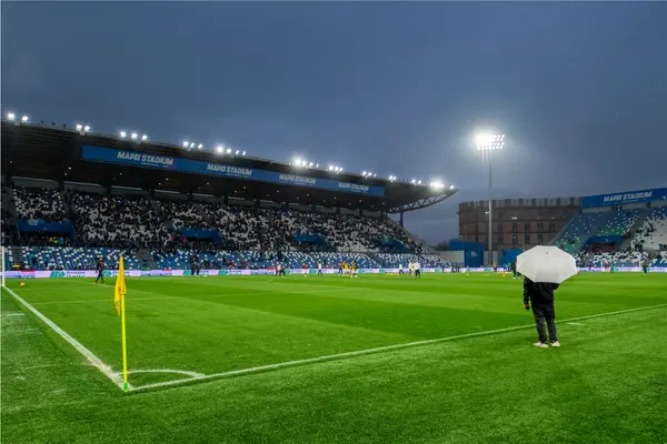 Mapei stadium at night with a person standing pitch side with an umbrella. The pitch is being illuminated by sports floodlight 'Altis' from Thorn