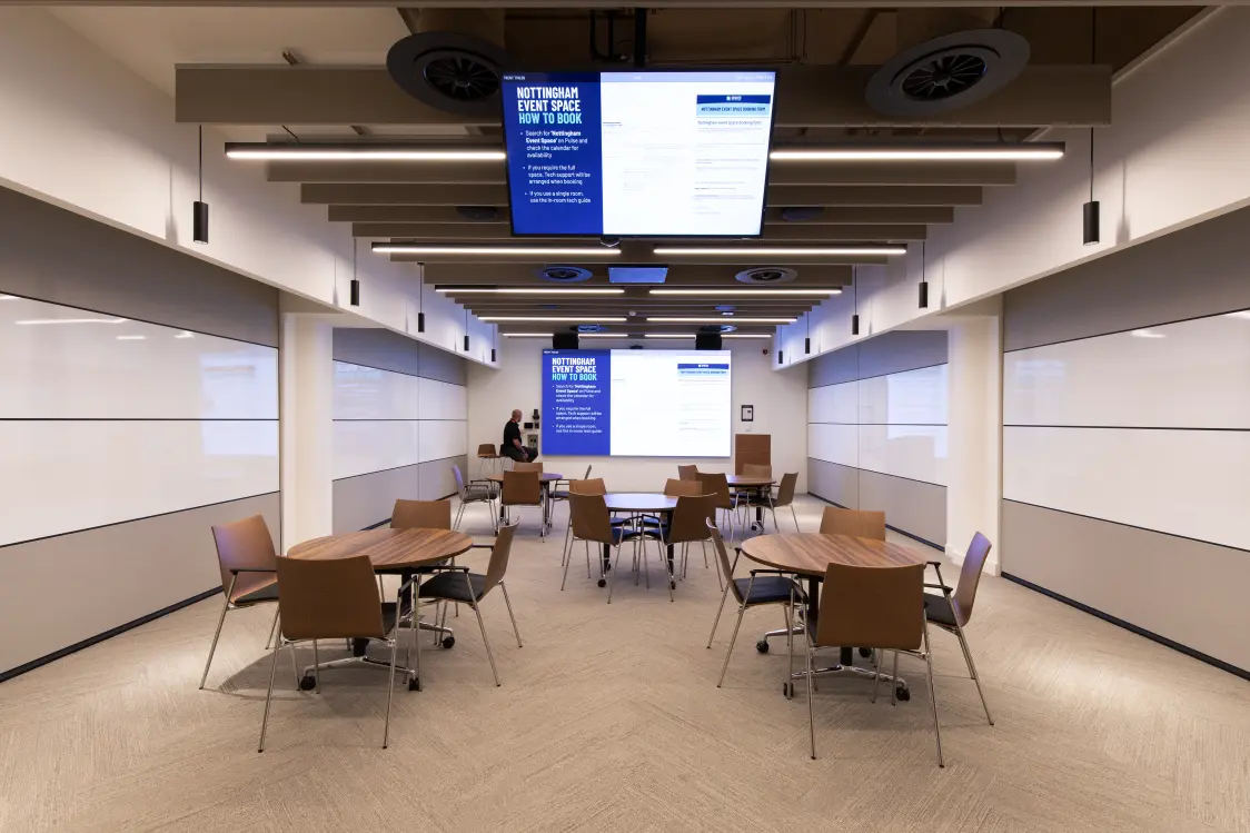Capital One, Nottingham - Flexible event space with round tables, chairs, large presentation screens, and configurable wall panels for meetings and workshops