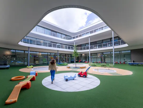 Cour intérieure adaptée aux enfants du campus MINT Care avec une architecture ludique et un éclairage Zumtobel.