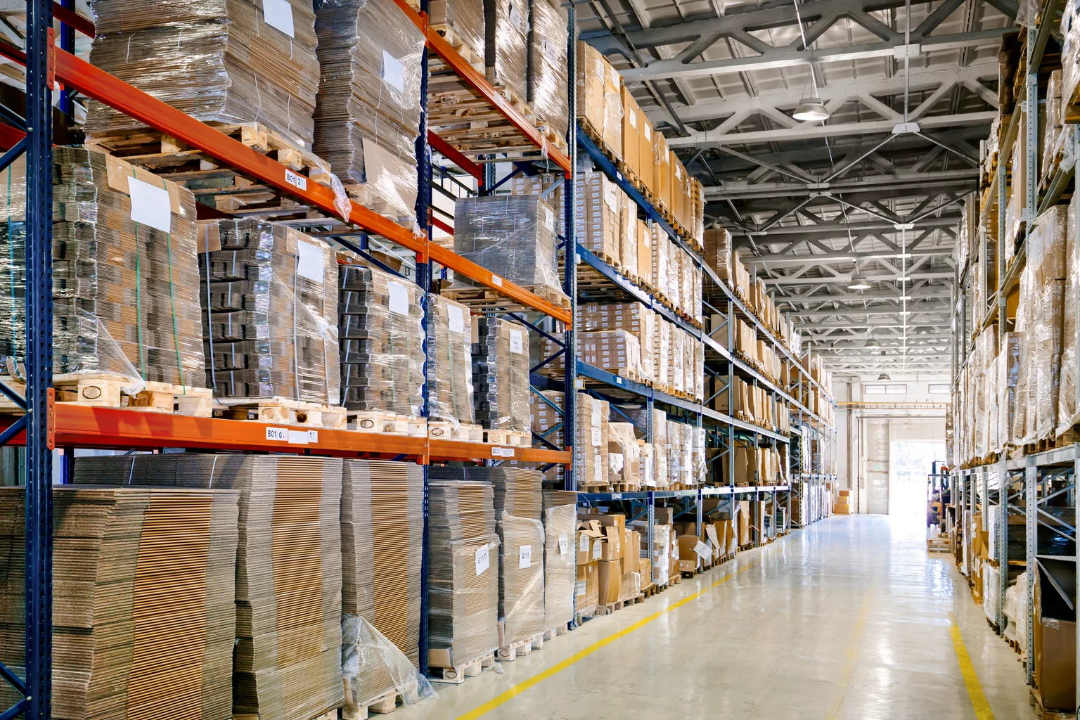 Zone logistique avec des rayonnages hauts remplis de boîtes et de palettes, l’espace étant éclairé par Thorn Lighting