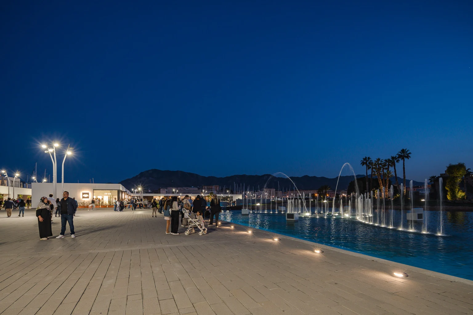 Eine städtische Promenade in Italien, auf der Menschen die Landschaft und die Wassershow genießen