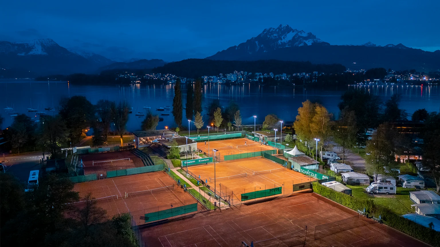Un court de tennis au loin, avec un seul terrain illuminé grâce aux commandes d'éclairage.