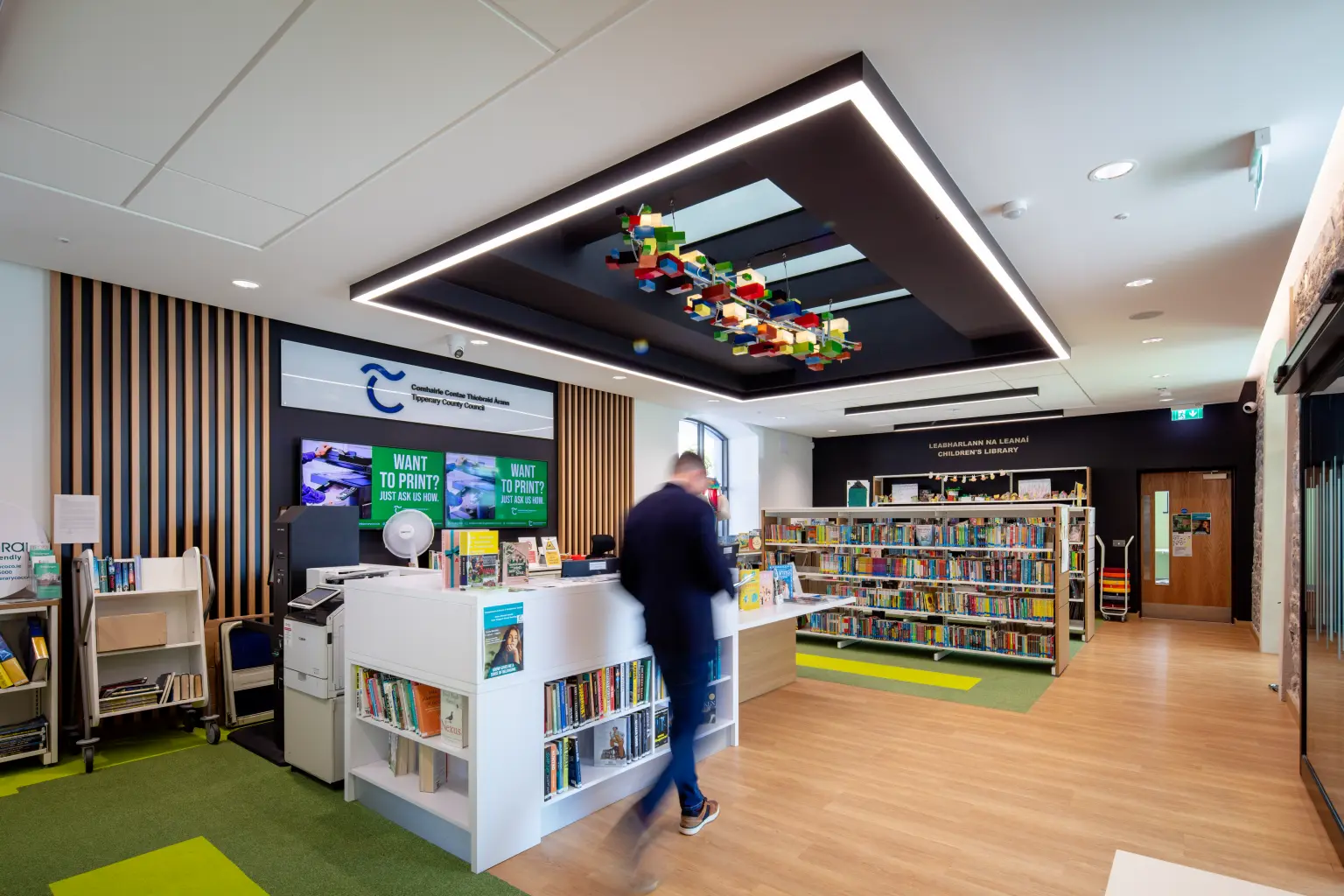 Templemore Library and Enterprise Centre, Tipperary - A man walking through a stylish, modern library featuring elegant bookshelves