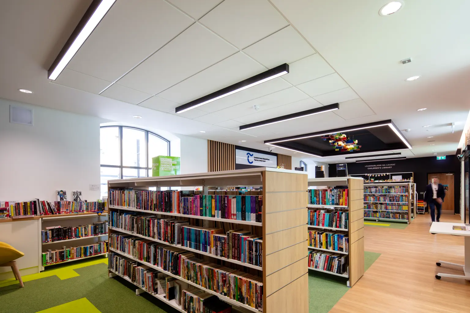 Templemore Library and Enterprise Centre, Tipperary - A man walking through a stylish and contemporary library filled with elegant book shelves