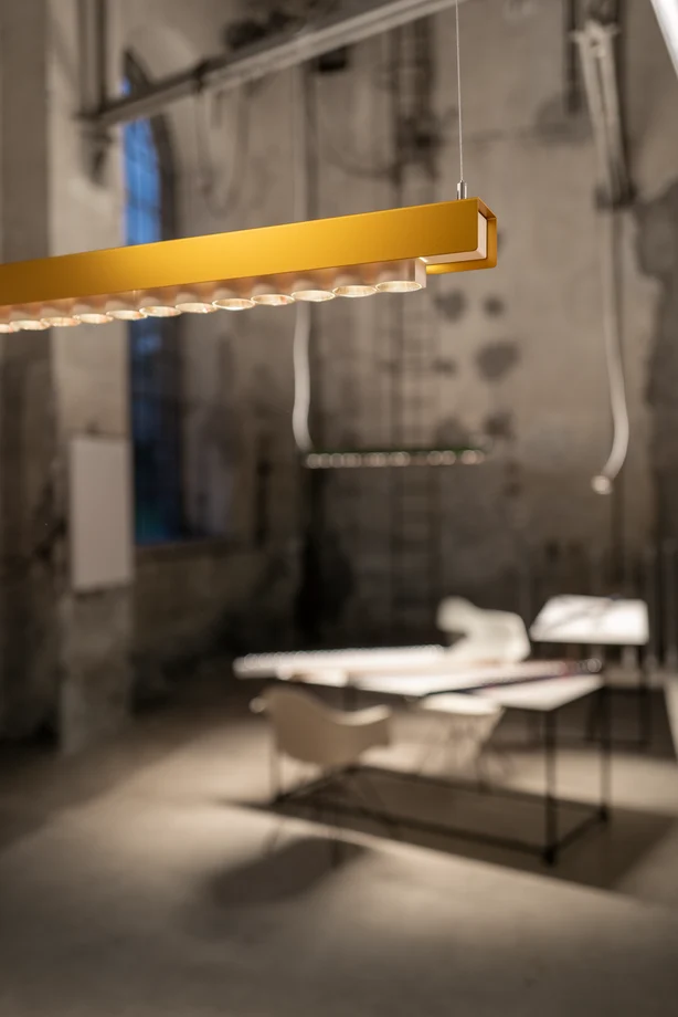 Luminaire Izura jaune suspendu dans une pièce.