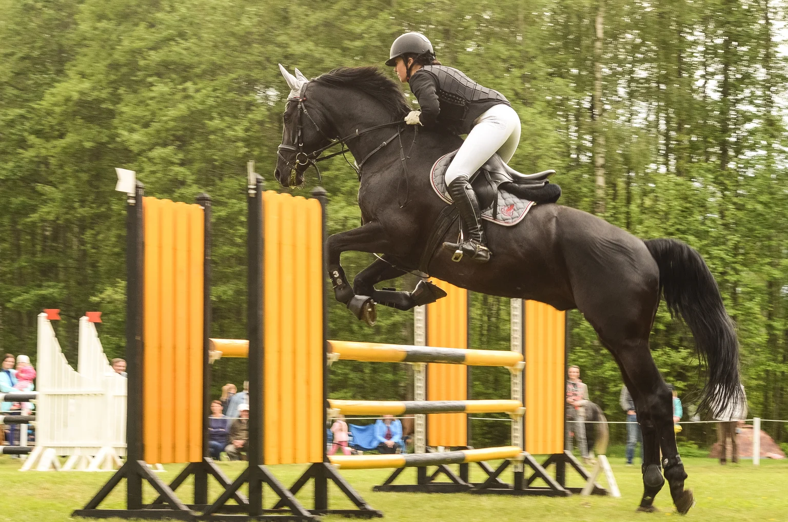 Une cavalière faisant sauter son cheval par-dessus un obstacle en pleine compétition.