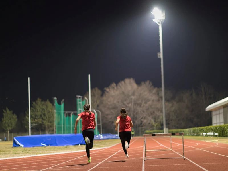 An athletics track being illuminated at night by Thorn Lighting for runners