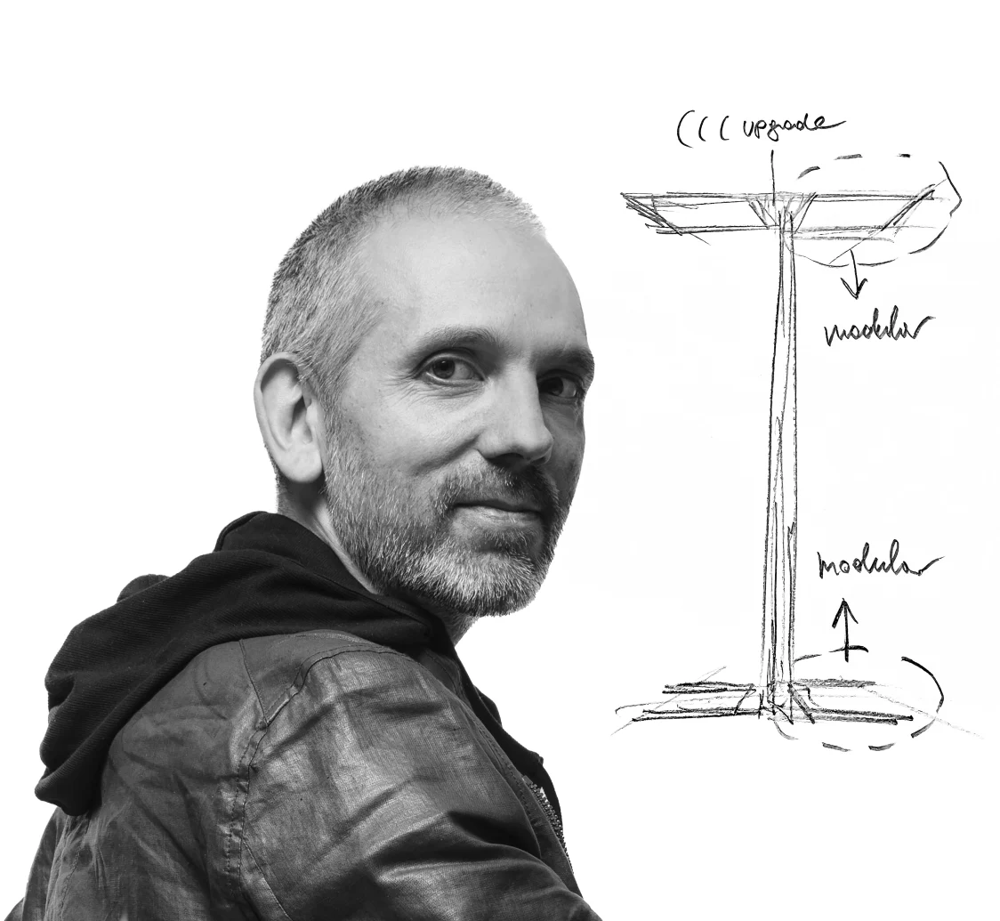 Le designer Harald Gründl avec des dessins du légendaire luminaire sur pied ARTELEA. L’image est en noir et blanc et a un style artistique. 