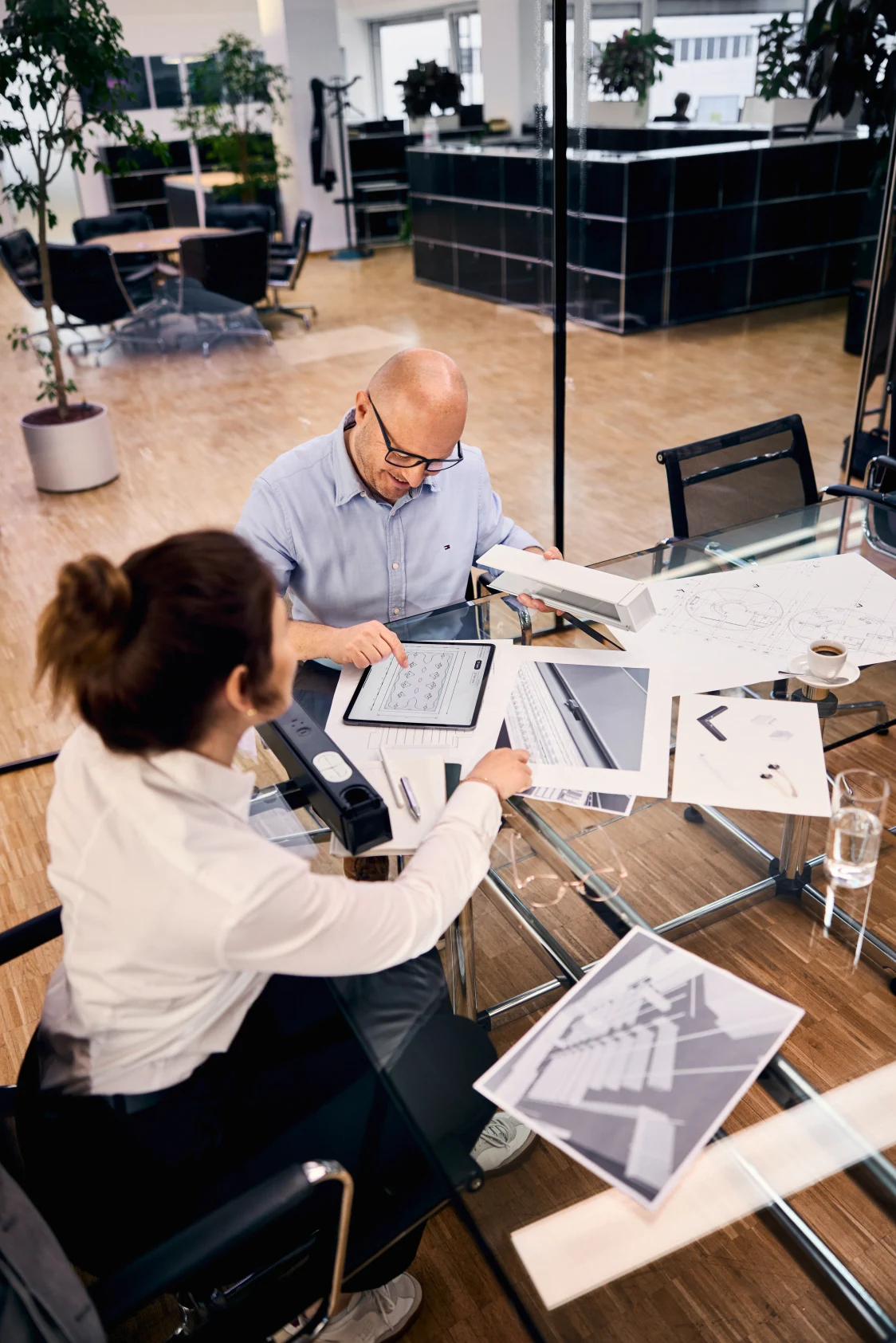 Deux personnes assises à un bureau. Ils travaillent avec du papier et des notes.