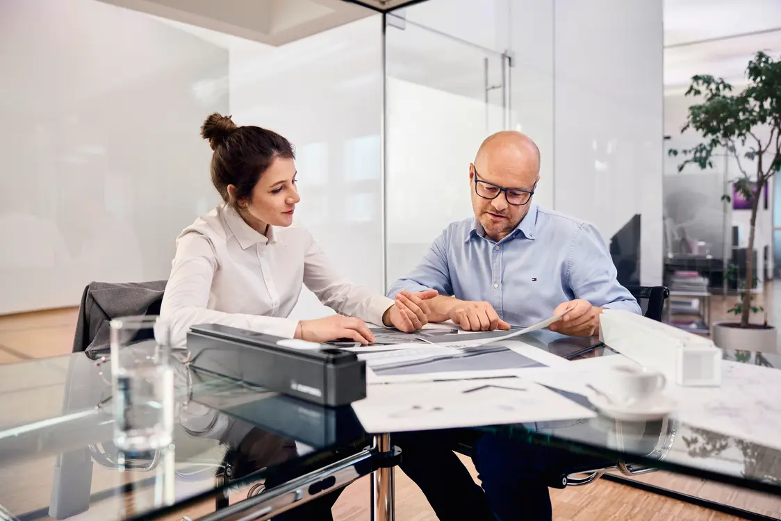 Two people working on a desk with paper.