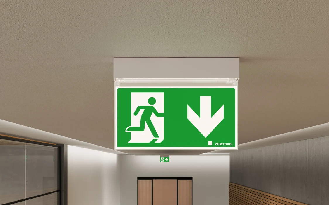 Nahaufnahme einer CROSSIGN PRO Sicherheitsleuchte von Zumtobel in einem modernen Flur – zeigt das Rettungszeichen klar und unaufdringlich im Normalbetrieb.