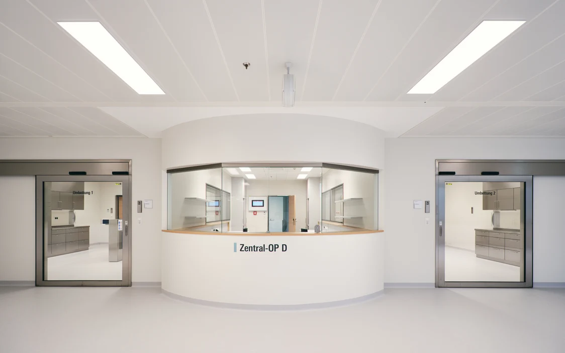 Moderner Zentral-OP-Bereich im Universitätsklinikum St. Pölten mit Glasfront und automatischen Türen – hygienische Architektur und präzise Beleuchtungslösung.