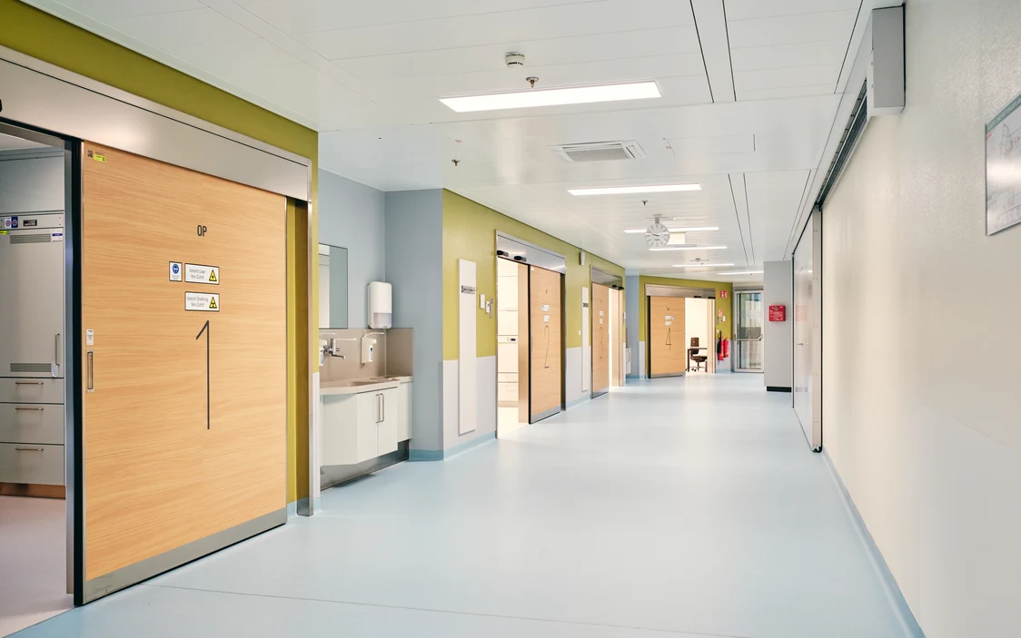 Moderner Krankenhausflur mit hygienischem Design und integrierter Beleuchtungslösung von Zumtobel für optimale Lichtqualität in medizinischen Bereichen.