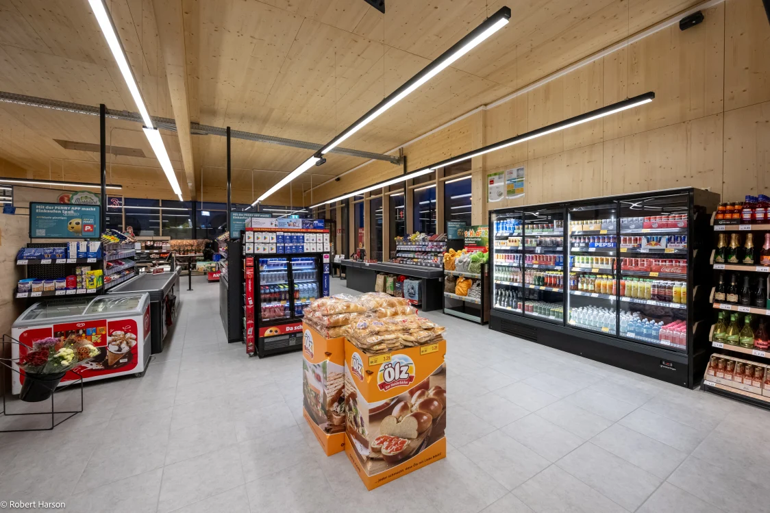 Interior view of the PENNY store in Weiden am See with energy-efficient LED lighting, wooden architecture, and refrigerated shelves for drinks and food.