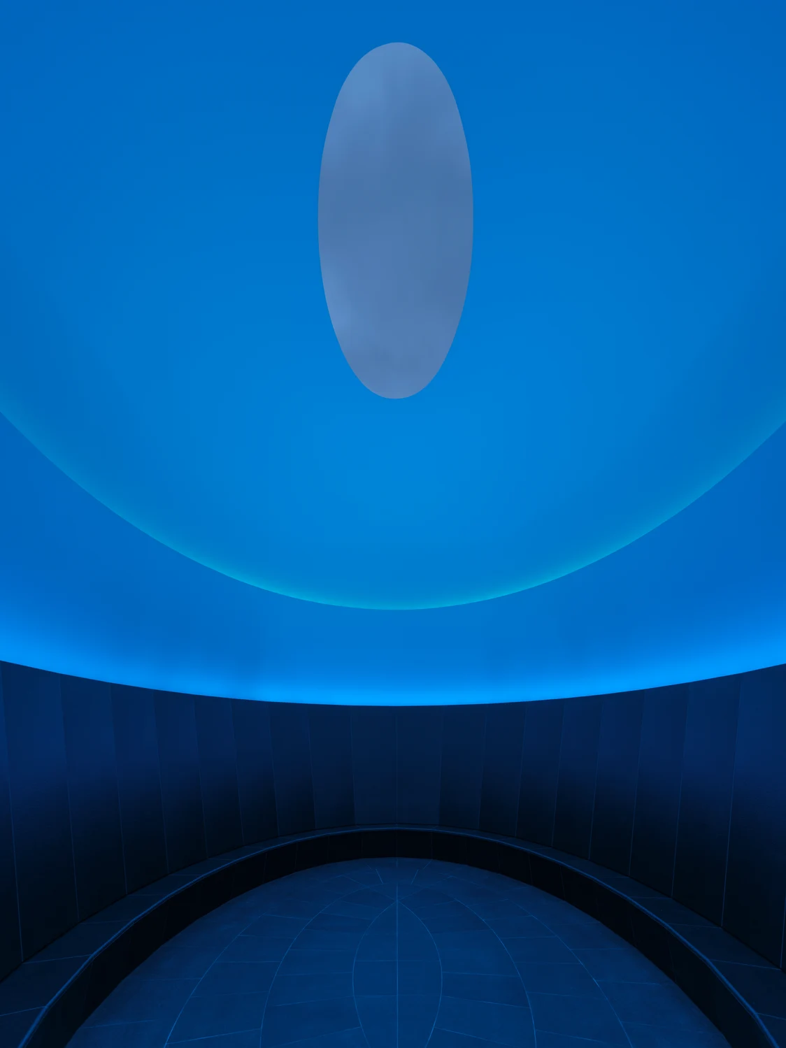 Innenansicht eines Skyspace von James Turrell im Kinderspital Zürich: elliptische Öffnung im Dach, umgeben von intensivem Blau, das durch präzise Lichtgestaltung von Zumtobel erzeugt wird.