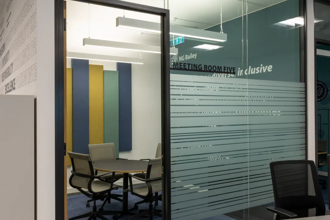 NG Bailey Headquarters, White Rose Office Park - A sophisticated cellular meeting room with frosted front glass, featuring a round table, comfortable chairs, and sleek lighting.