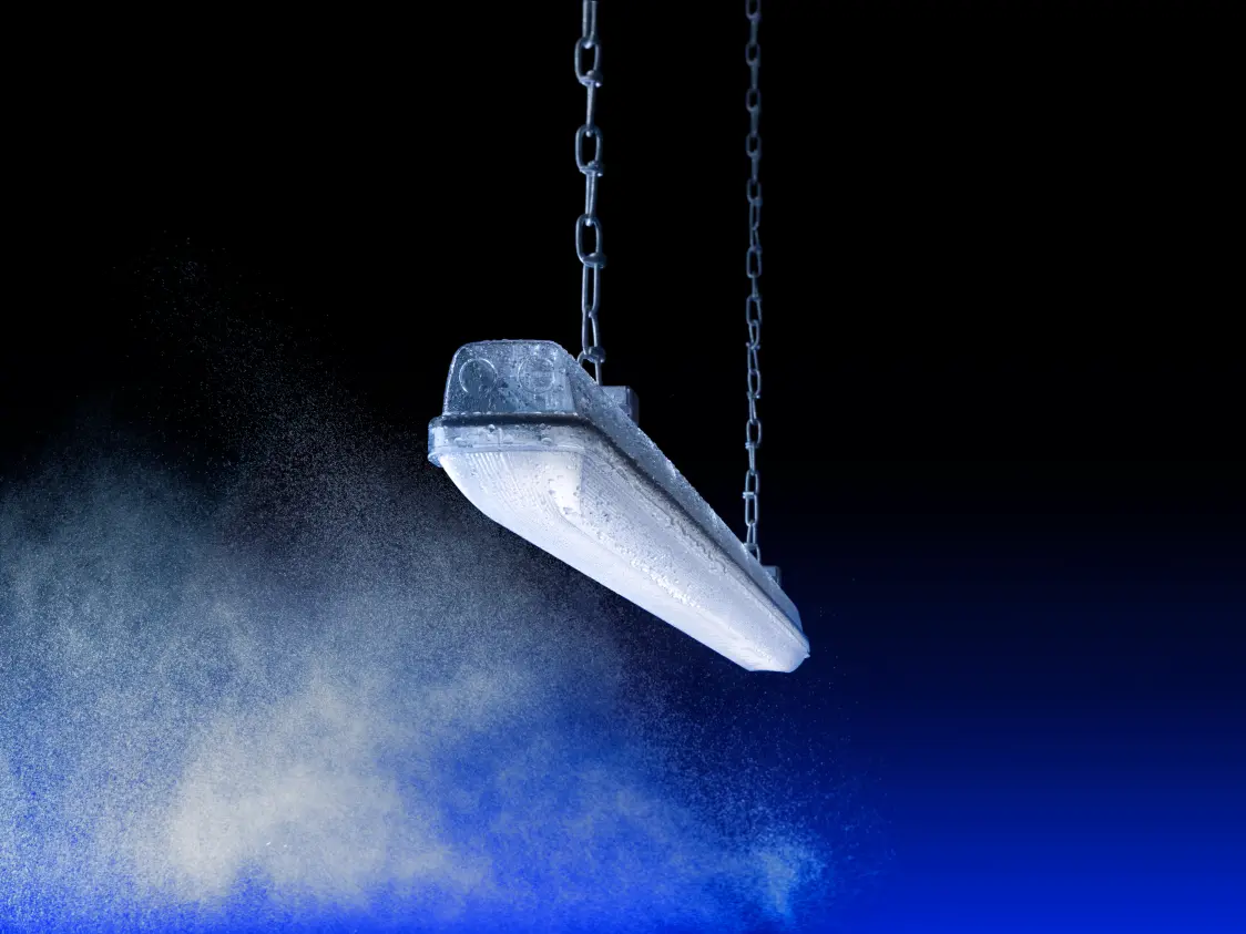 Una persona installa il sistema di gestione della luce AMPHIBIA su una parete di cemento in uno spazio industriale con un'illuminazione uniforme e chiara.