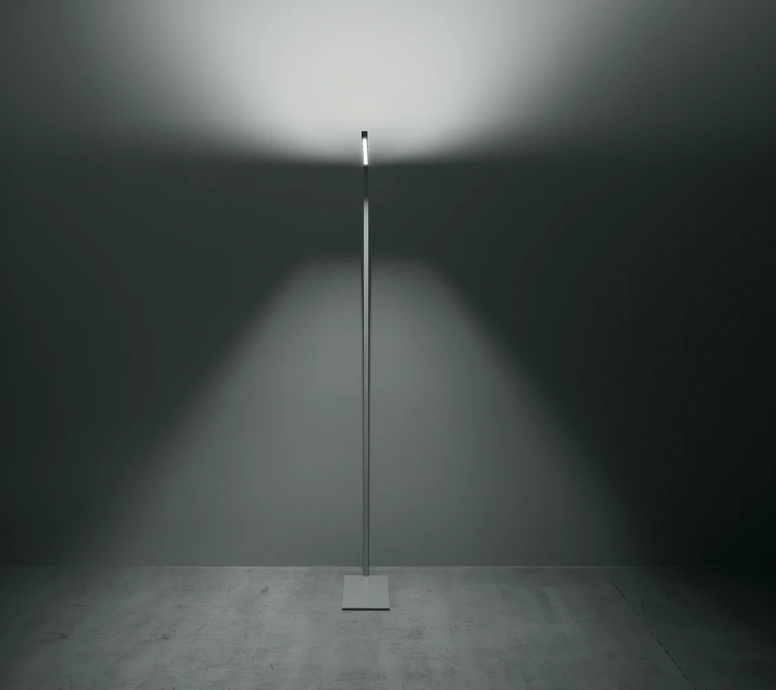  LINETIK Stehleuchte erzeugt eine schlichte, gleichmäßige Lichtverteilung an der Wand in einem modernen, minimalistisch eingerichteten Raum.
