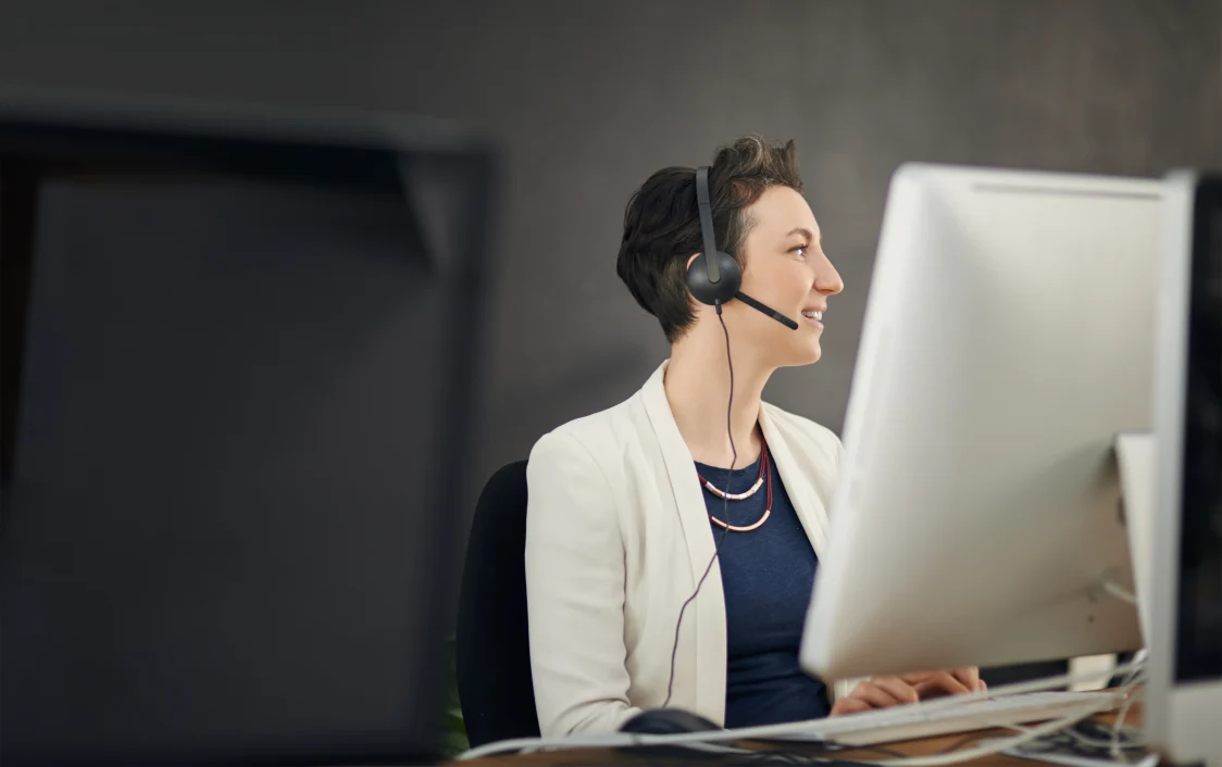 Frau sitz vor einem Bildschirm mit einem Headset auf dem Kopf