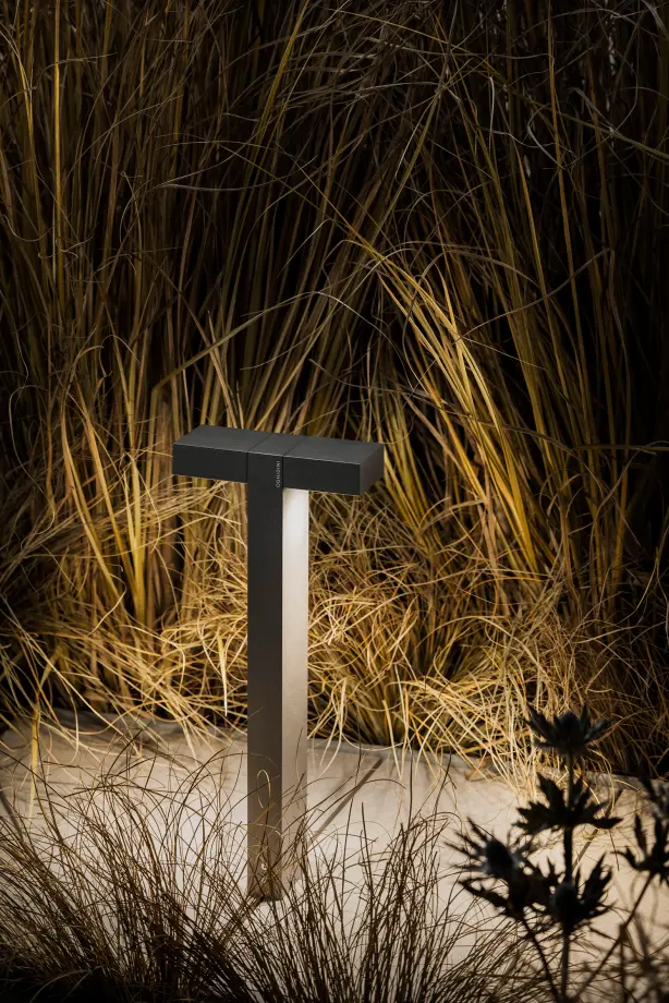 Outdoor Pollerleuchte Compatto P in einem Gartenbeet bei Nacht