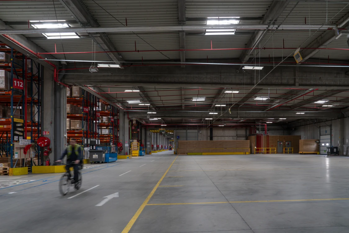 IKEA distribution center interior with open logistics workspace, storage racking, and energy-efficient LED lighting providing uniform illumination for warehouse operations.