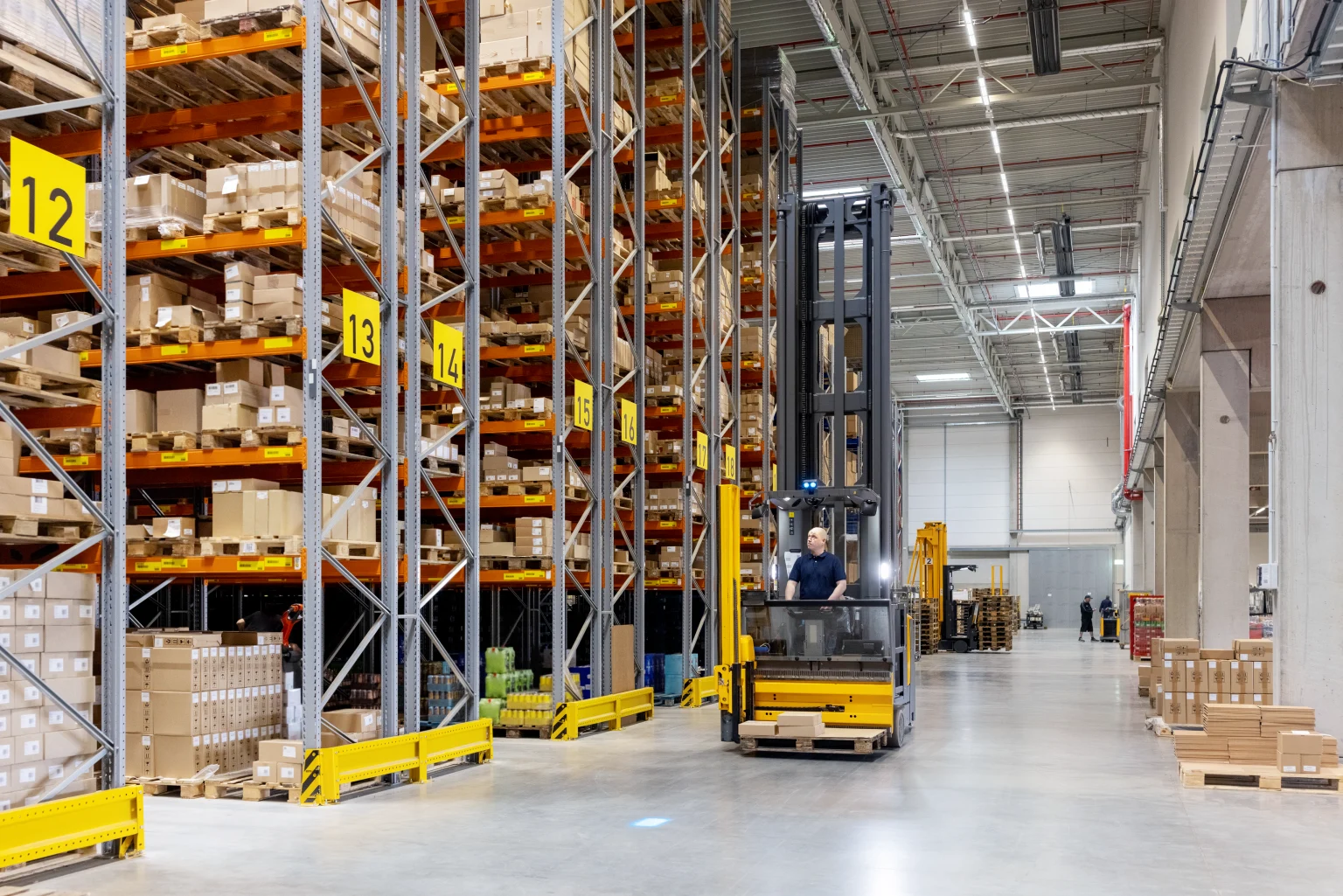 Logistics centre with high racking full of boxes and pallets with the space being lit by Thorn 's Titus highbays